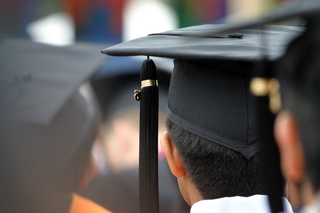 Backside view of a student wearing black graduation cap.